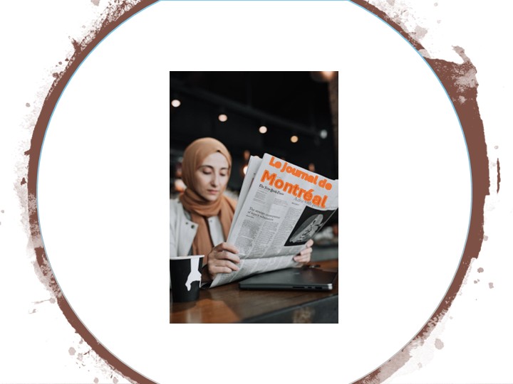 Une femme avec un voile marron qui est assise à une table sur laquelle ce trouve une tasse et un ordinateur portable et qui lit le «journal de Montréal»