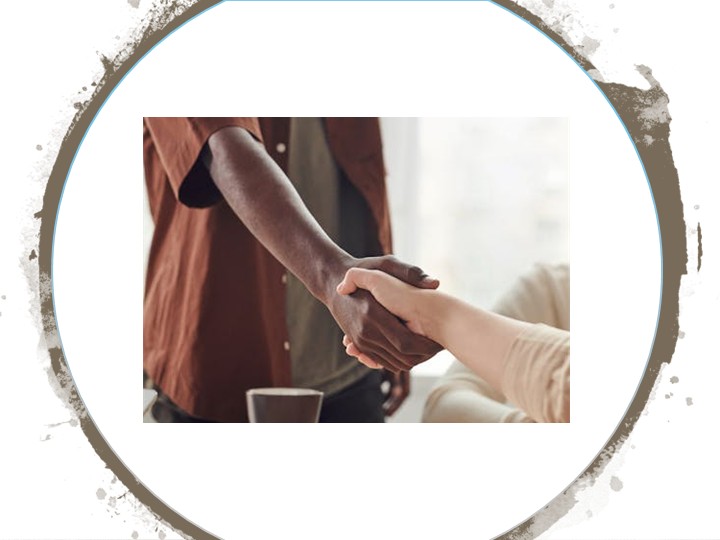 Deux personnes de races différentes se serrant la main au-dessus d'une tasse. L'une est debout et la seconde, assise